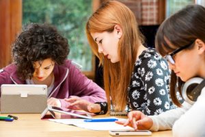 Three young students working on digital divices.